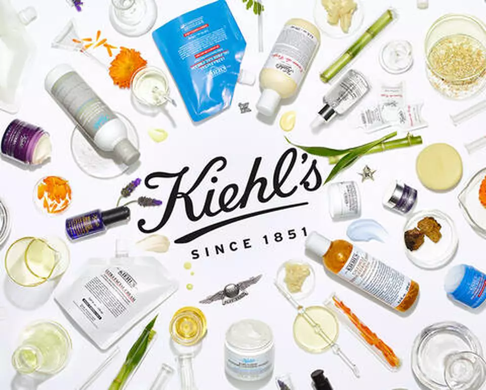 vista aerea productos cuidado de la piel, ingredientes naturales en un fondo blanco y el logo de Kiehl's en el centro