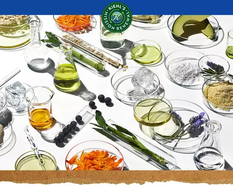 Ingredientes naturales y elementos de laboratorio sobre fondo blanco, con logo 'Kiehl's Mission Renew